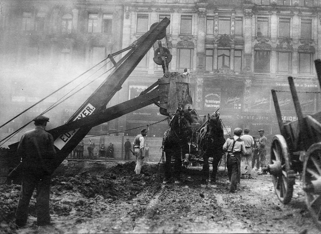 Leipzig, Markt um 1925 - Baustelle der Untergrundmessehalle - ausgebaggerte Erde wird auf ein Pferdewagen zum Abtransport mittels Bagger verladen, im Hintergrund: Markt 13-14 / <a href="https://commons.wikimedia.org/wiki/File:StadtAL_0563_BA_1988_27332.jpg">Stadtarchiv Leipzig</a>, <a href="https://creativecommons.org/licenses/by-sa/4.0">CC BY-SA 4.0</a>, via Wikimedia Commons